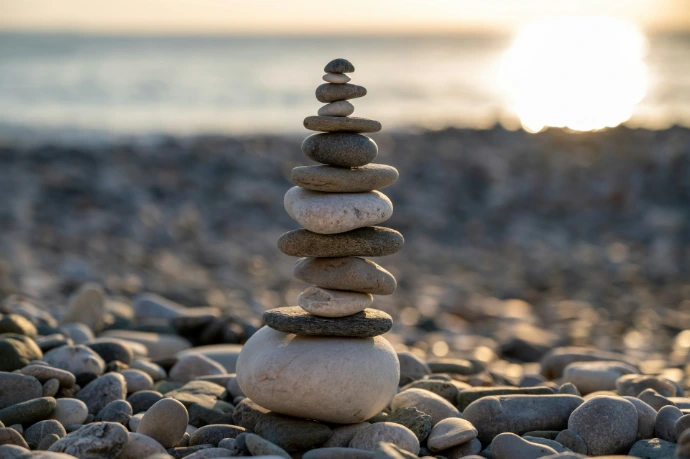 Stack of balanced stones on a pebble beach at sunset